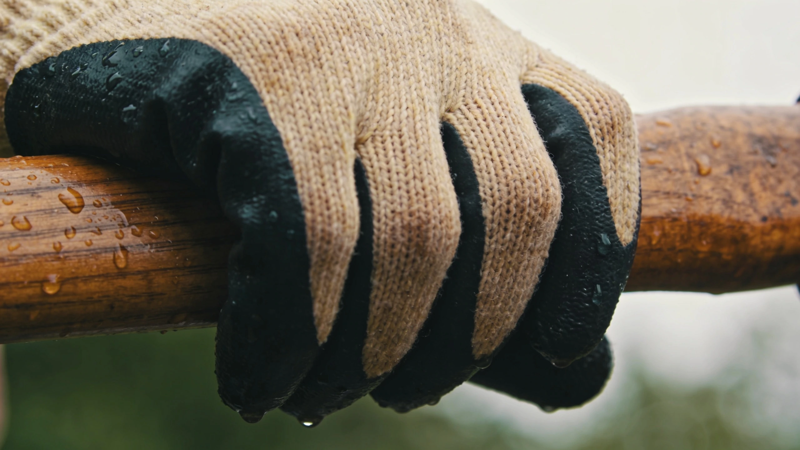 Nitrile coated gloves gripping a wet tool handle Knitted glove with a nitrile coated palm gripping a wet wooden spade handle