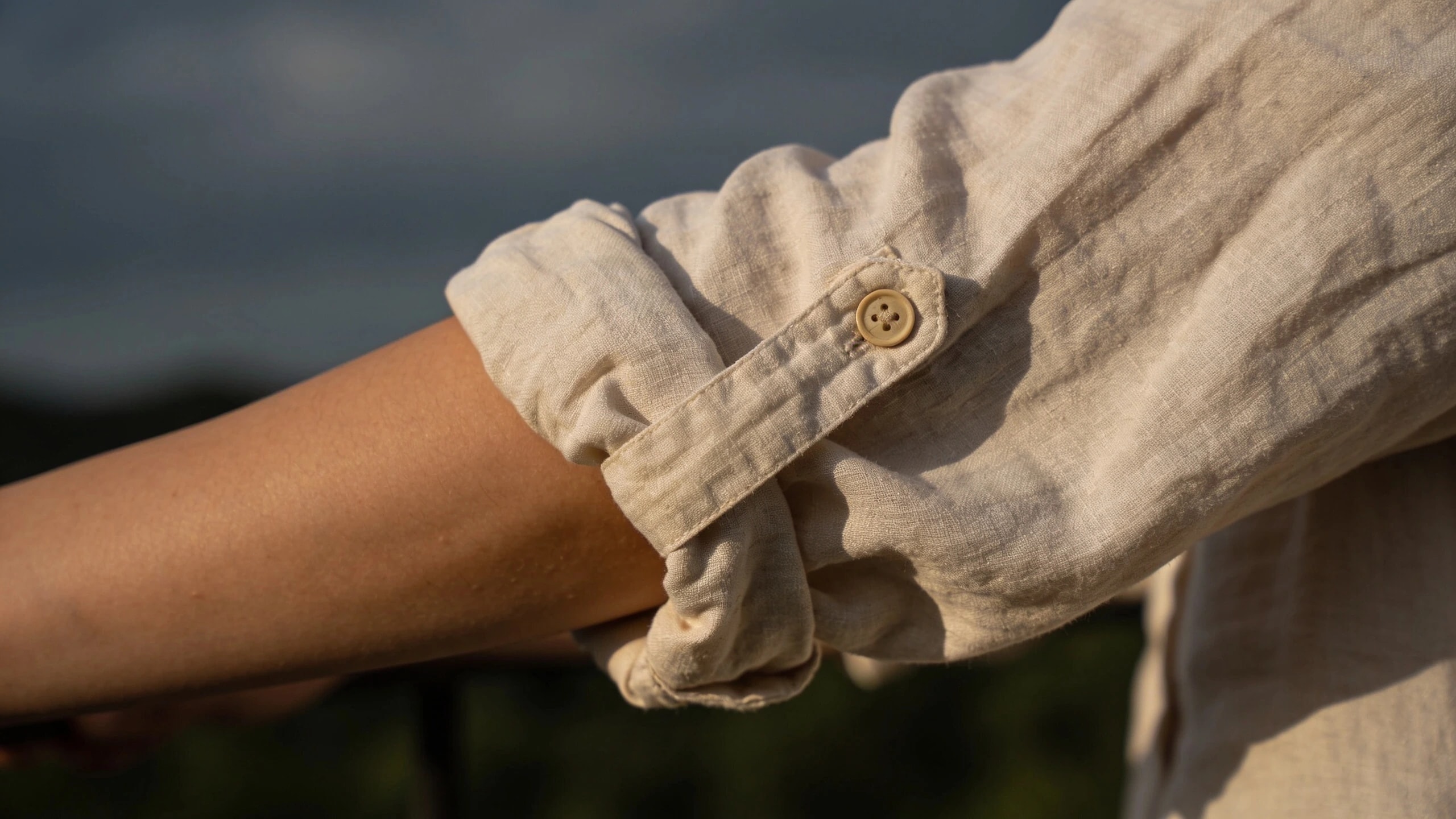 A loose long-sleeved shirt for sun protection Loose light long-sleeved shirt sleeve rolled to the forearm with a button tab in sun